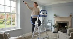 A person using a platform step ladder with an integrated tool tray to paint coving in a British living room.