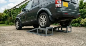Heavy-duty steel car ramps supporting a Land Rover Discovery 4x4 on a textured concrete driveway in the UK, showcasing robust construction for large vehicles.