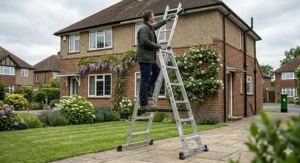 High-reach triple extension combination ladder leaning against a brick wall for roof-line and gutter access on a residential property.