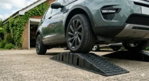 Close-up of extra-wide black polymer car ramps accommodating the wide tyre width of a modern British SUV to ensure stability and safety.
