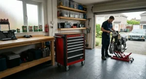 A photorealistic scene showing a mechanic working on a classic British motorbike, with a lockable red and black mobile tool cabinet in the foreground and a historic car on the driveway outside.