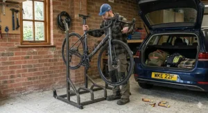 A cyclist removing a road bike from a freestanding bike rack in a garage next to an estate car packed for a weekend trip.