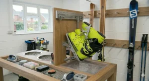 A floor-standing ski storage rack with a removable bottom plastic drip tray catching water droplets from melting snow on the ski boots and bindings.