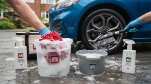 A bucket of soapy water and a specialist wheel brush used for safely cleaning alloy wheels.