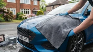 Using a large, plush microfibre drying towel to dry a car bodywork without scratching.
