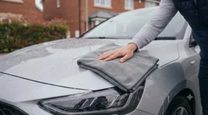 Ultra-absorbent microfibre drying towel preventing water spots on a freshly washed car paint surface.