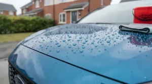 Hydrophobic water beading effect on a freshly waxed car bonnet, illustrating paintwork protection against British weather.