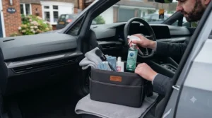 Scrubbing muddy rubber and fabric car floor mats using a stiff-bristled brush included in a car valet kit.