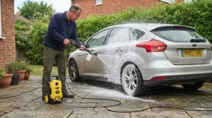 Using an affordable pressure washer with a foam lance to wash soapy water off a hatchback car in a driveway.