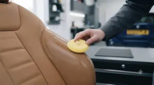 Nourishing dry leather car seats with a protective conditioning balm using a foam applicator pad.