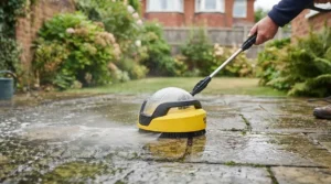 Close-up of a budget pressure washer surface attachment cleaning muddy paving slabs on a patio.