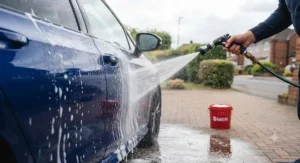 Rinsing soapy residue off a car with a pressure washer from top to bottom during a regular weekend wash.