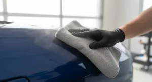 Wiping away dried polish residue with a soft microfibre towel to reveal a high-gloss finish.