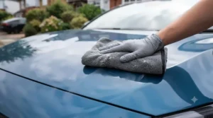 Buffing dried paste wax off car paintwork with a clean microfibre cloth