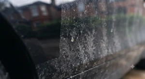 Close-up of a lower car door panel showing accumulated winter road grime and dried salt spray, contrasted sharply with a section that has been protected by paste wax, demonstrating the hydrophobic barrier and cleanliness.
